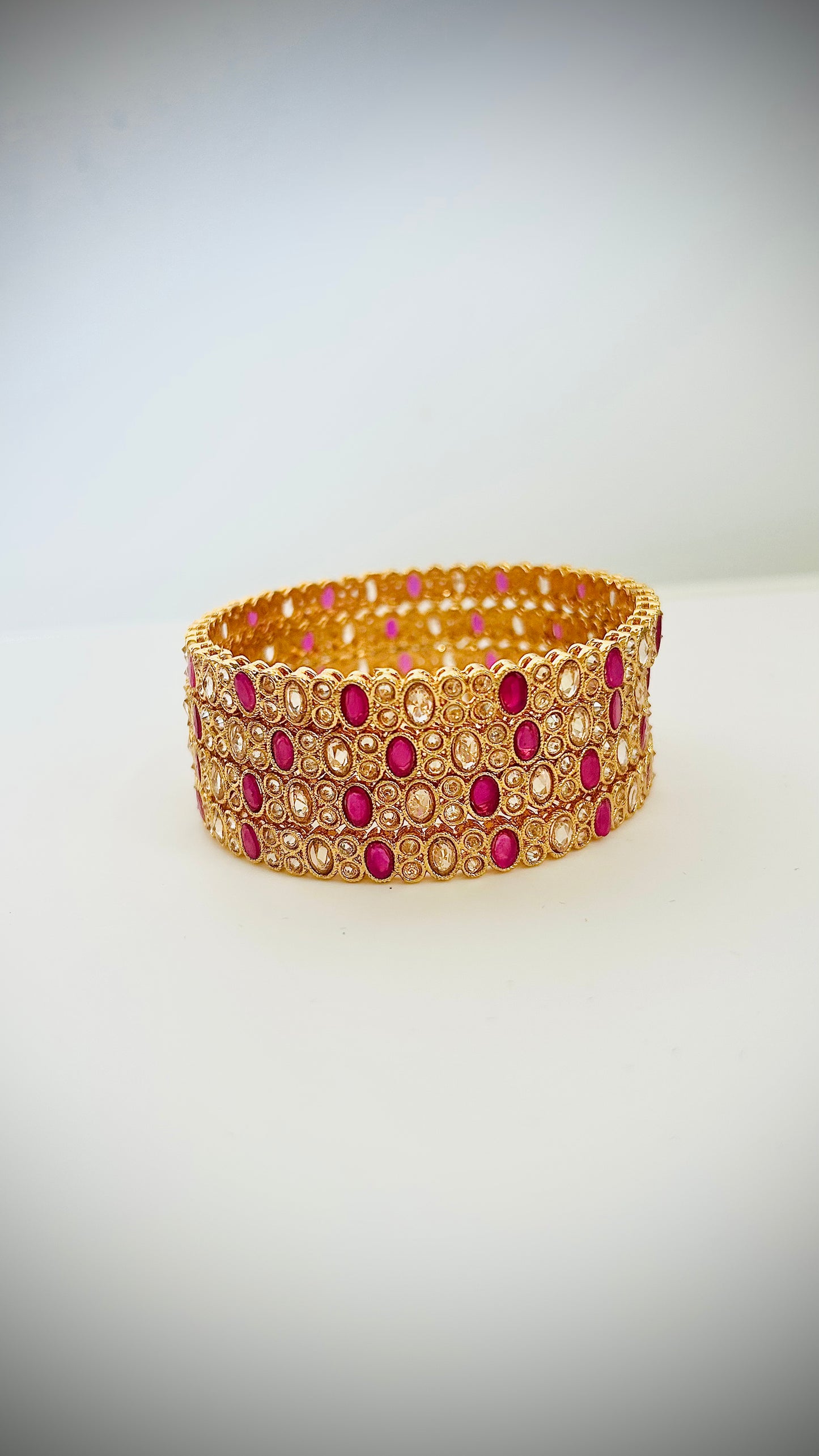 Set of 4 gold bangles with pink stones.