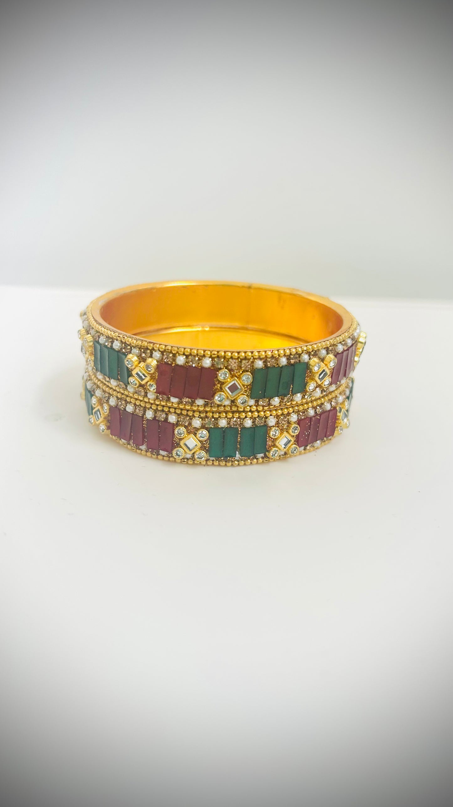 Pair of gold bangles with red and green stones