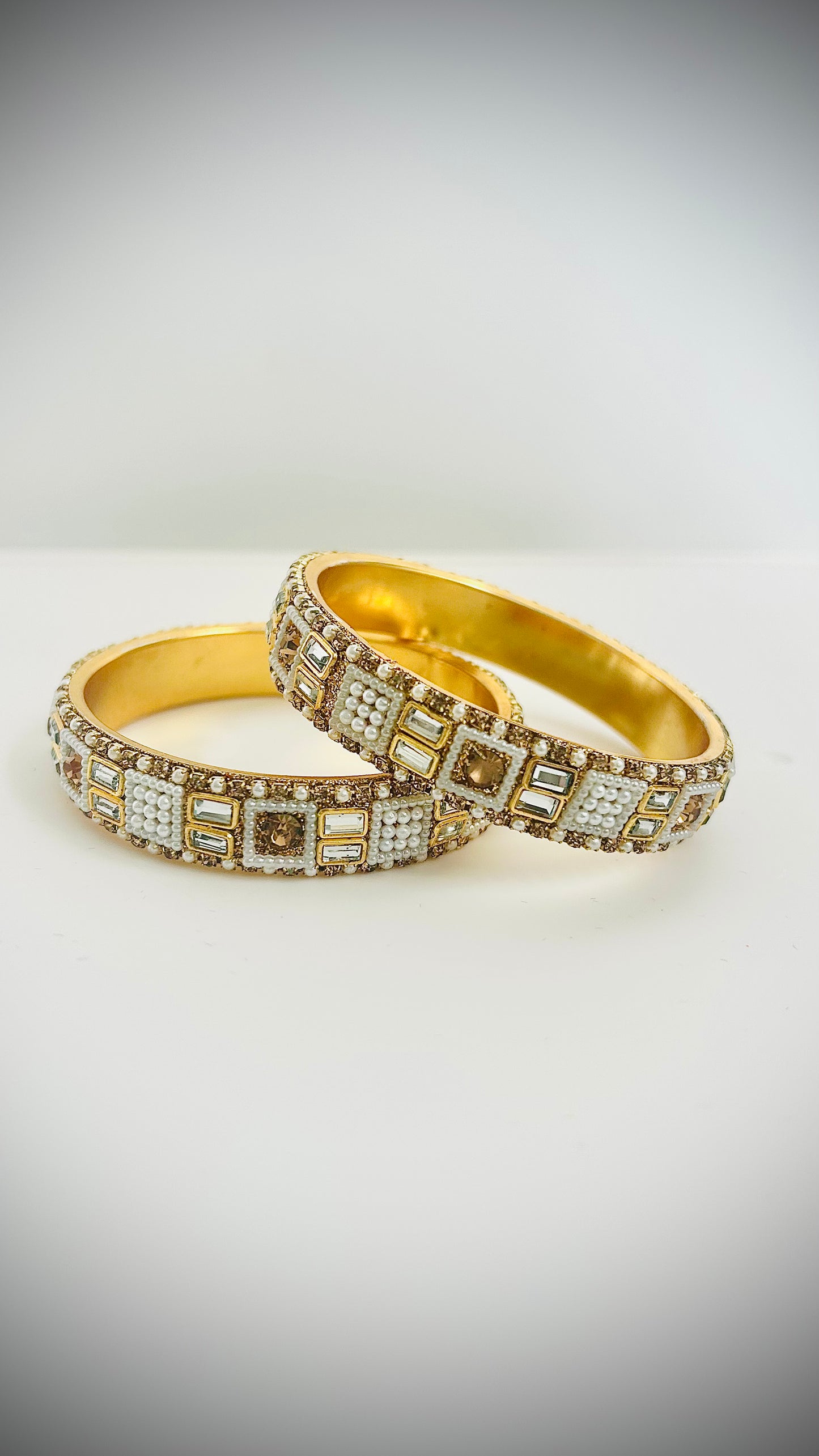 Two gold bracelets with white gemstones.