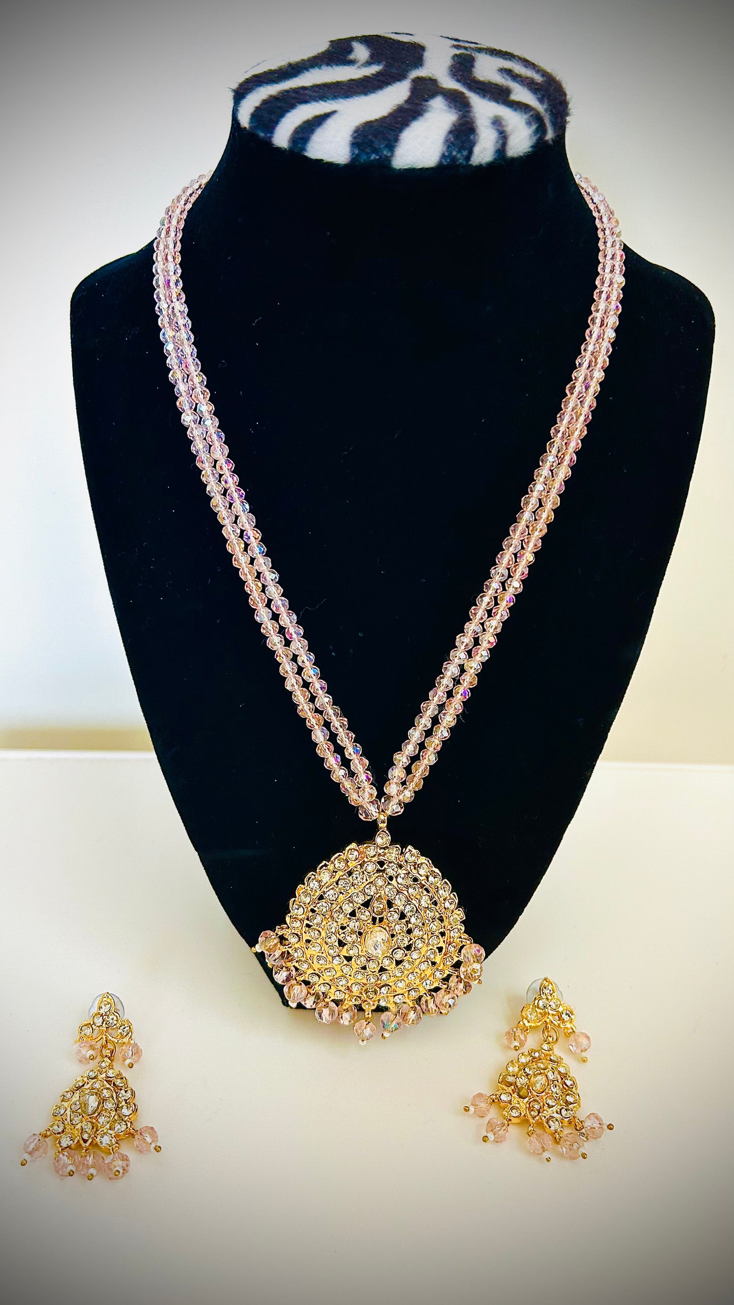 Jewelry set with necklace and earrings on a black stand against a white background