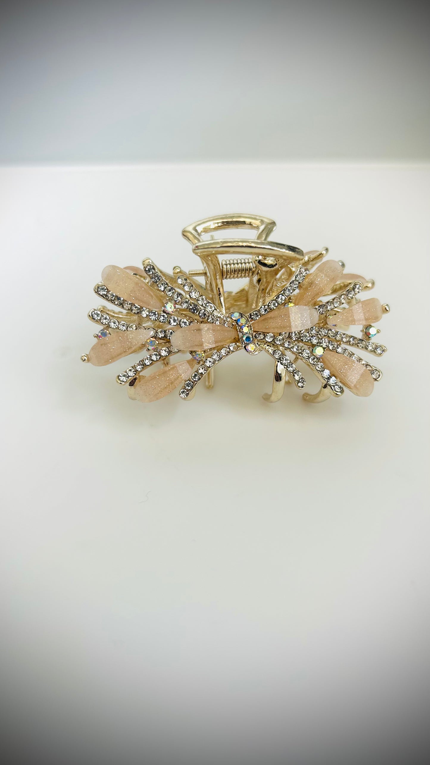 Goldand peach hair clip with decorative elements on a white background