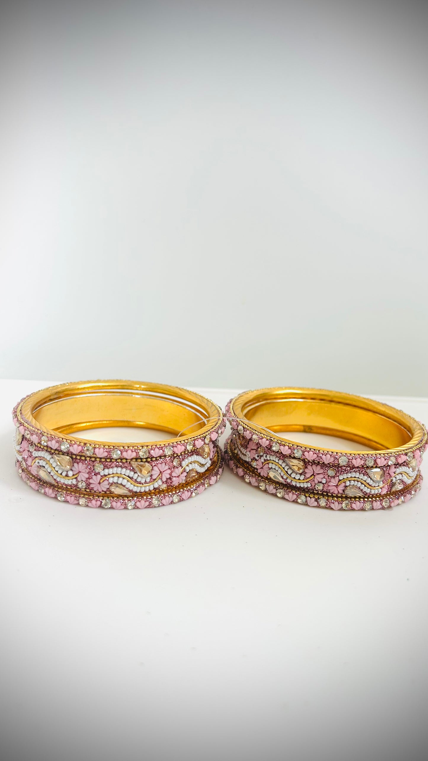 Set of gold bangles with pink and white stones