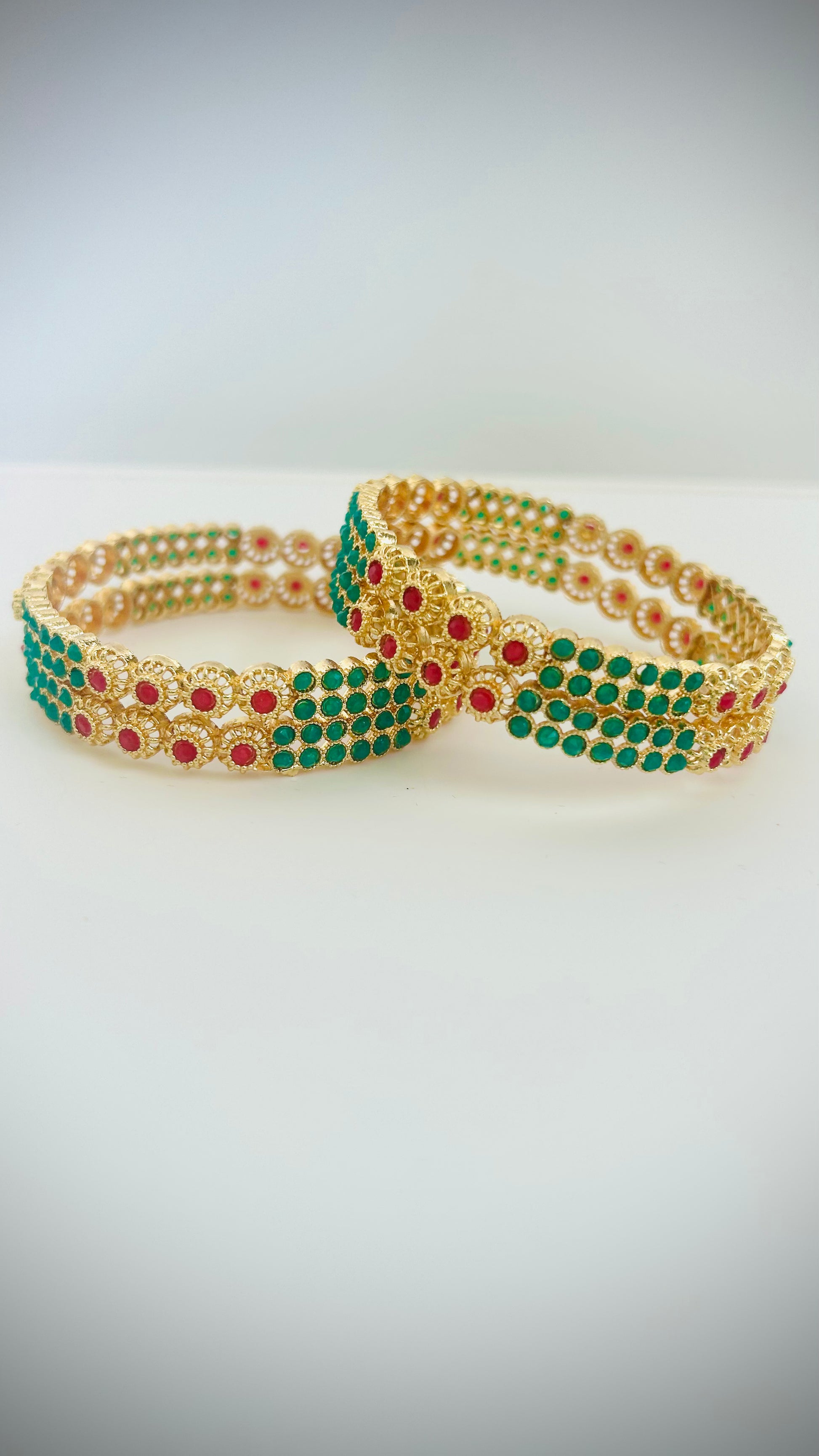 Gold bangles with green and red stones.