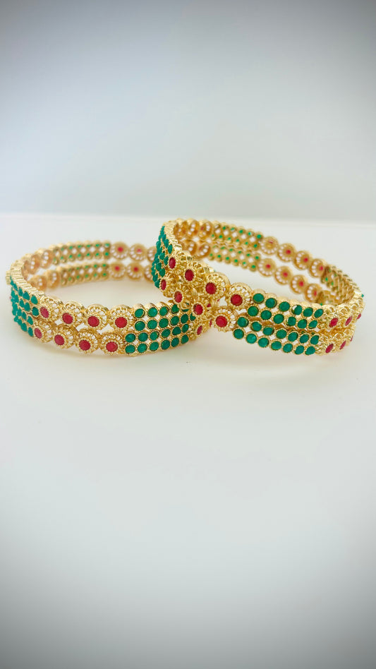 Gold bangles with green and red stones.