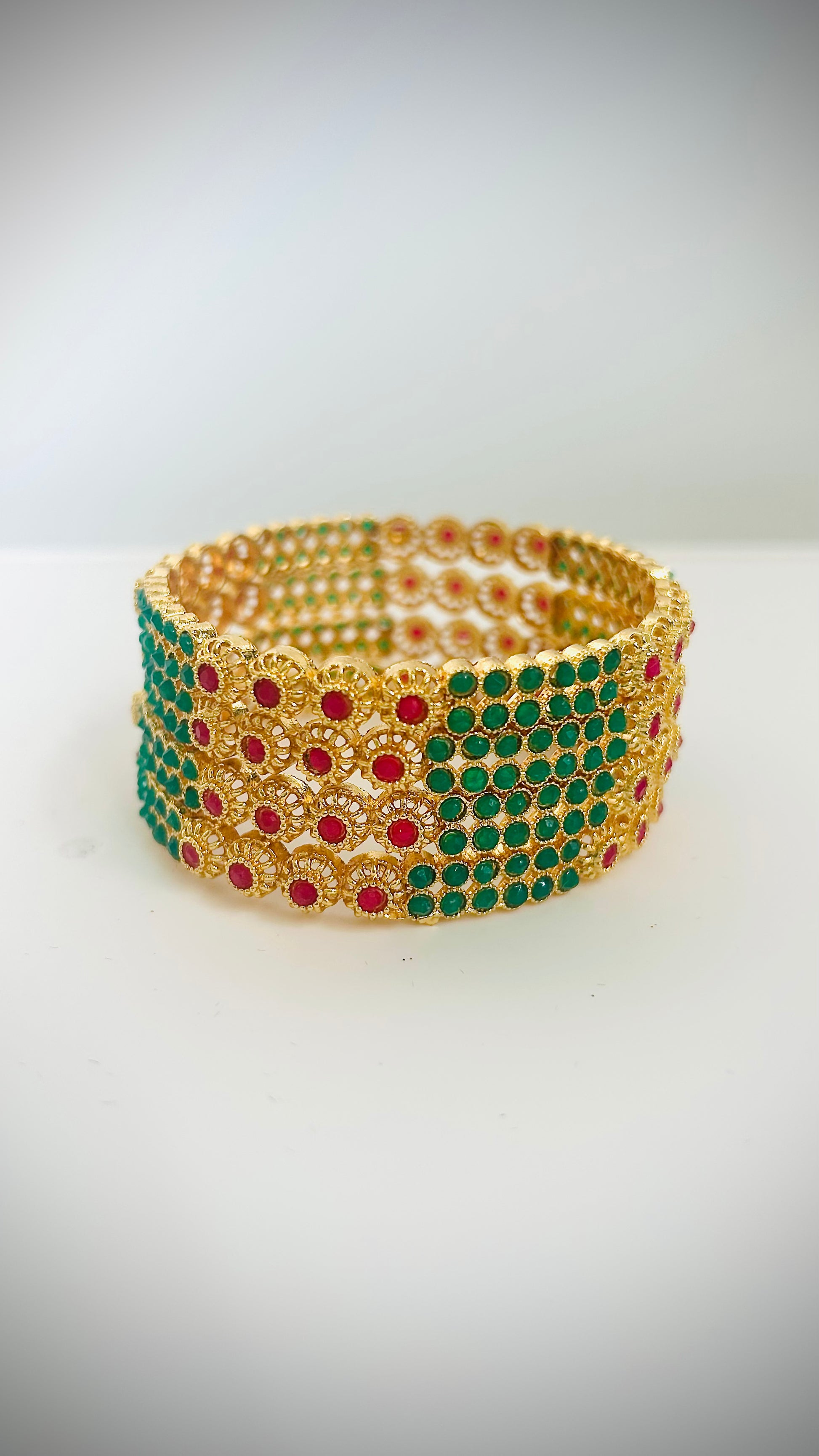 Gold bangles with green and red stones.