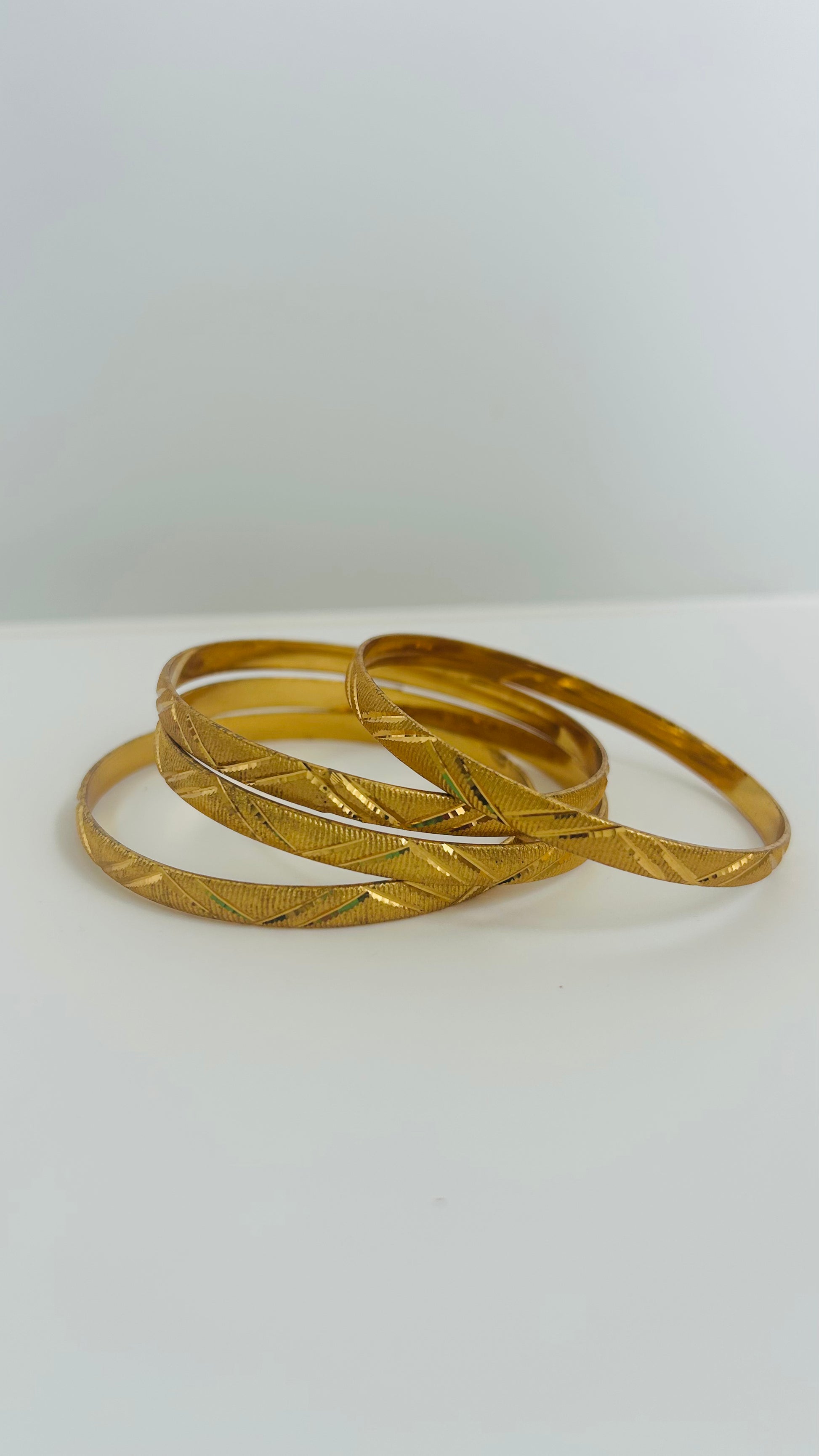 Four gold bangles stacked 
