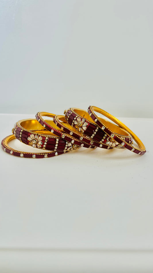 Set of maroon and gold bangles on a white background