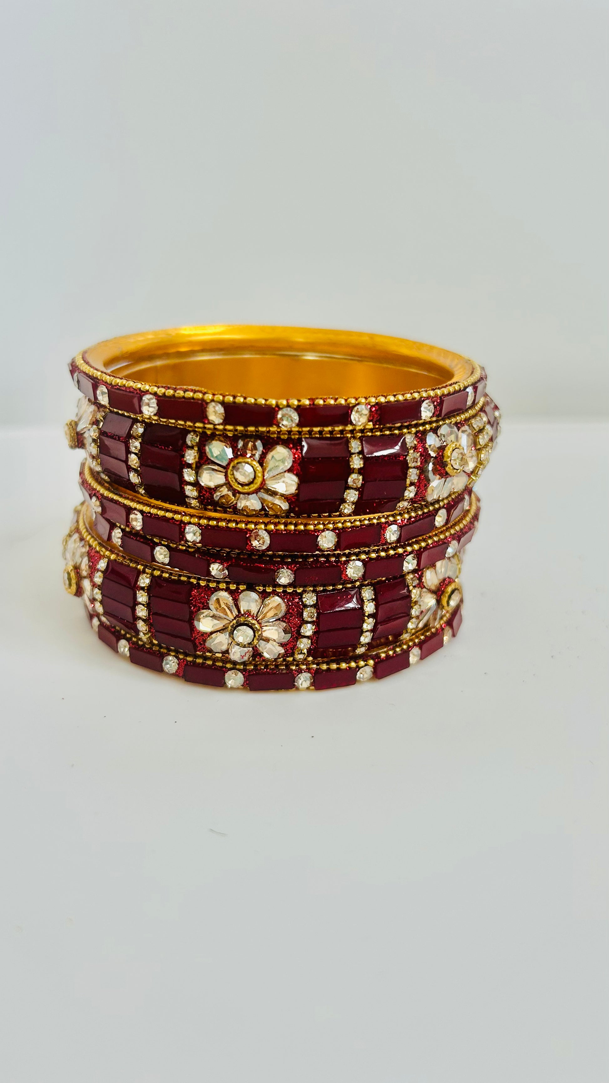 Set of maroon and gold bangles on a white background