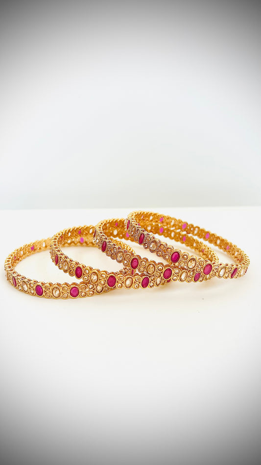 Set of 4 gold bangles with pink stones.