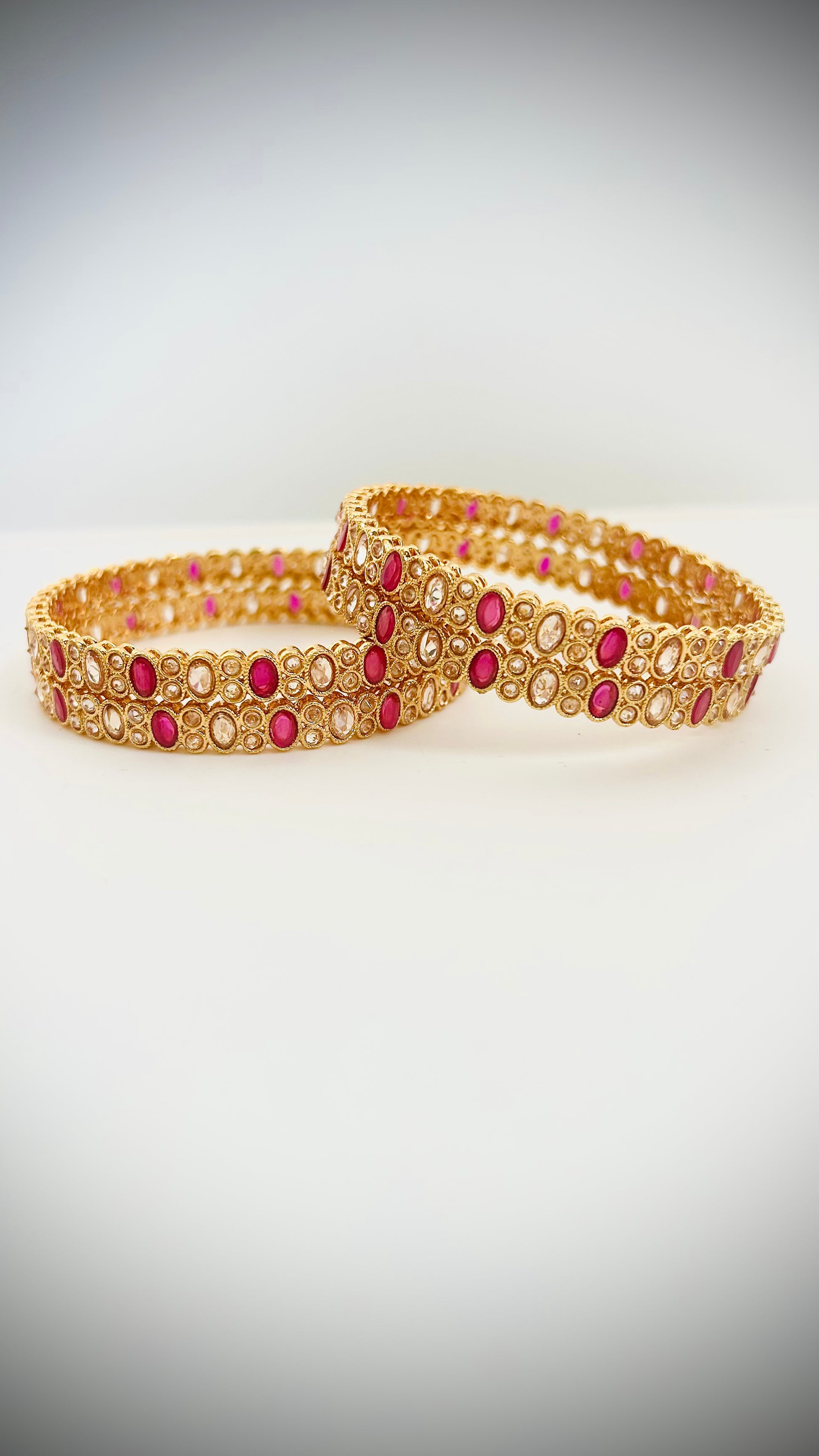 Set of 4 gold bangles with pink stones.