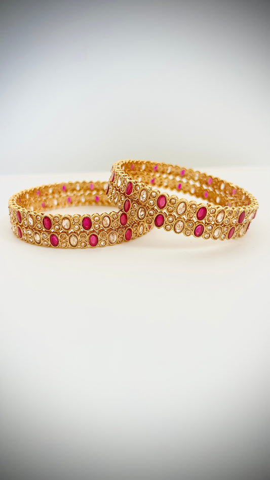 Set of 4 gold bangles with pink stones.