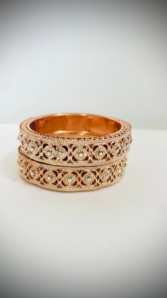 Stack of rose-gold bangles with intricate designs.