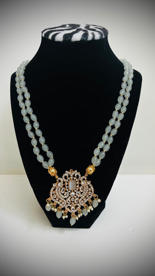 Necklace with a large decorative pendant on a black bust against a white background