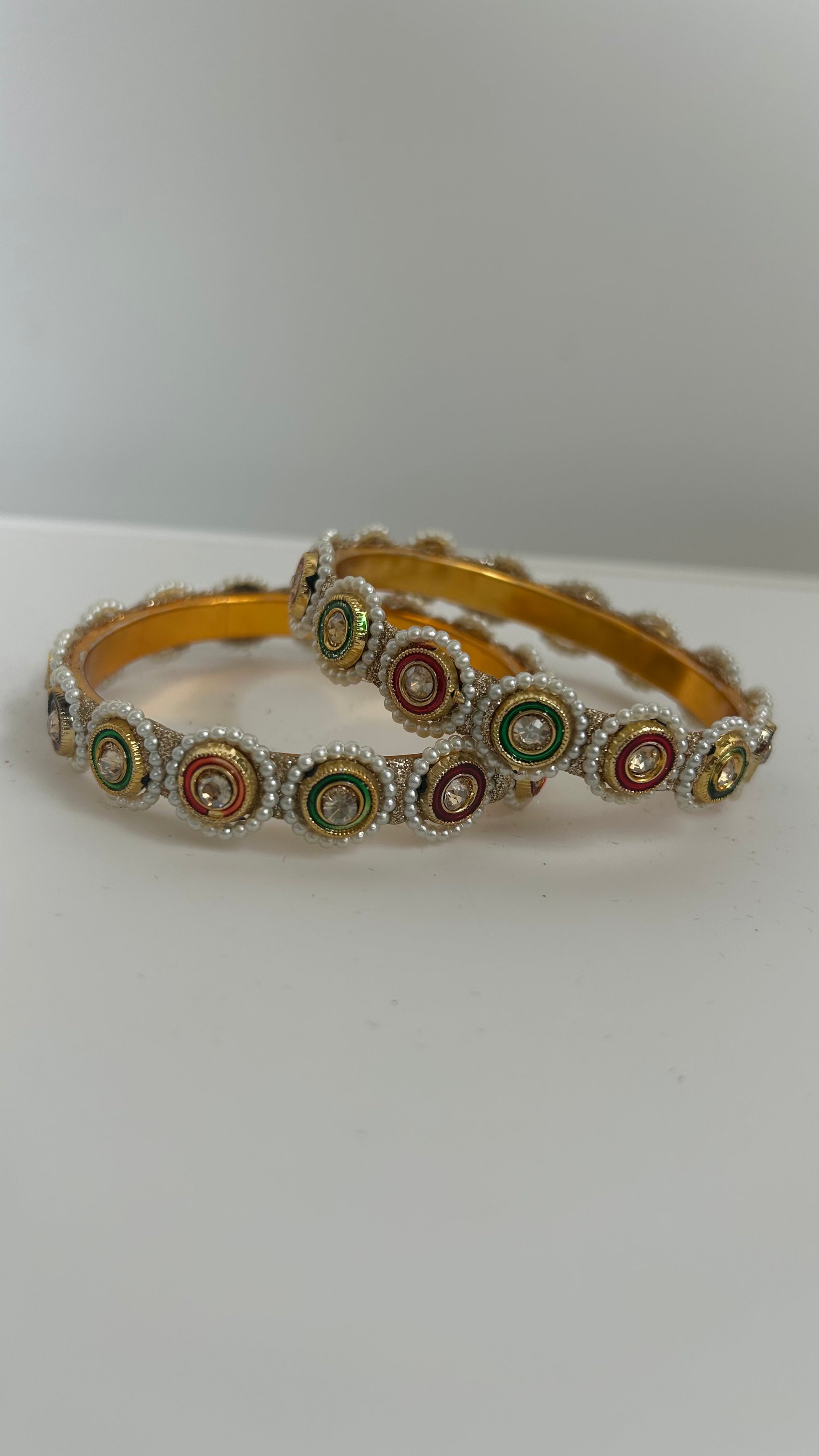 Gold bangles with colorful circular patterns.