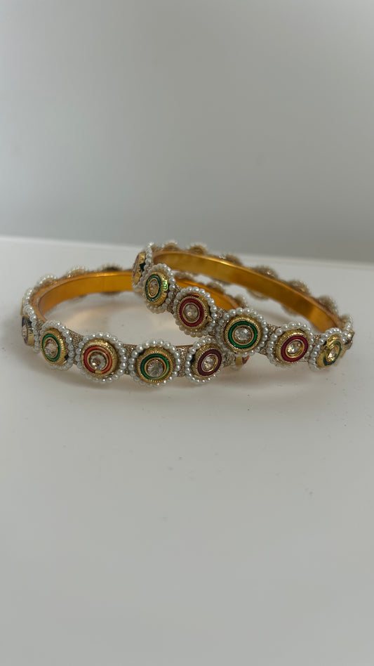 Gold bangles with colorful circular patterns.