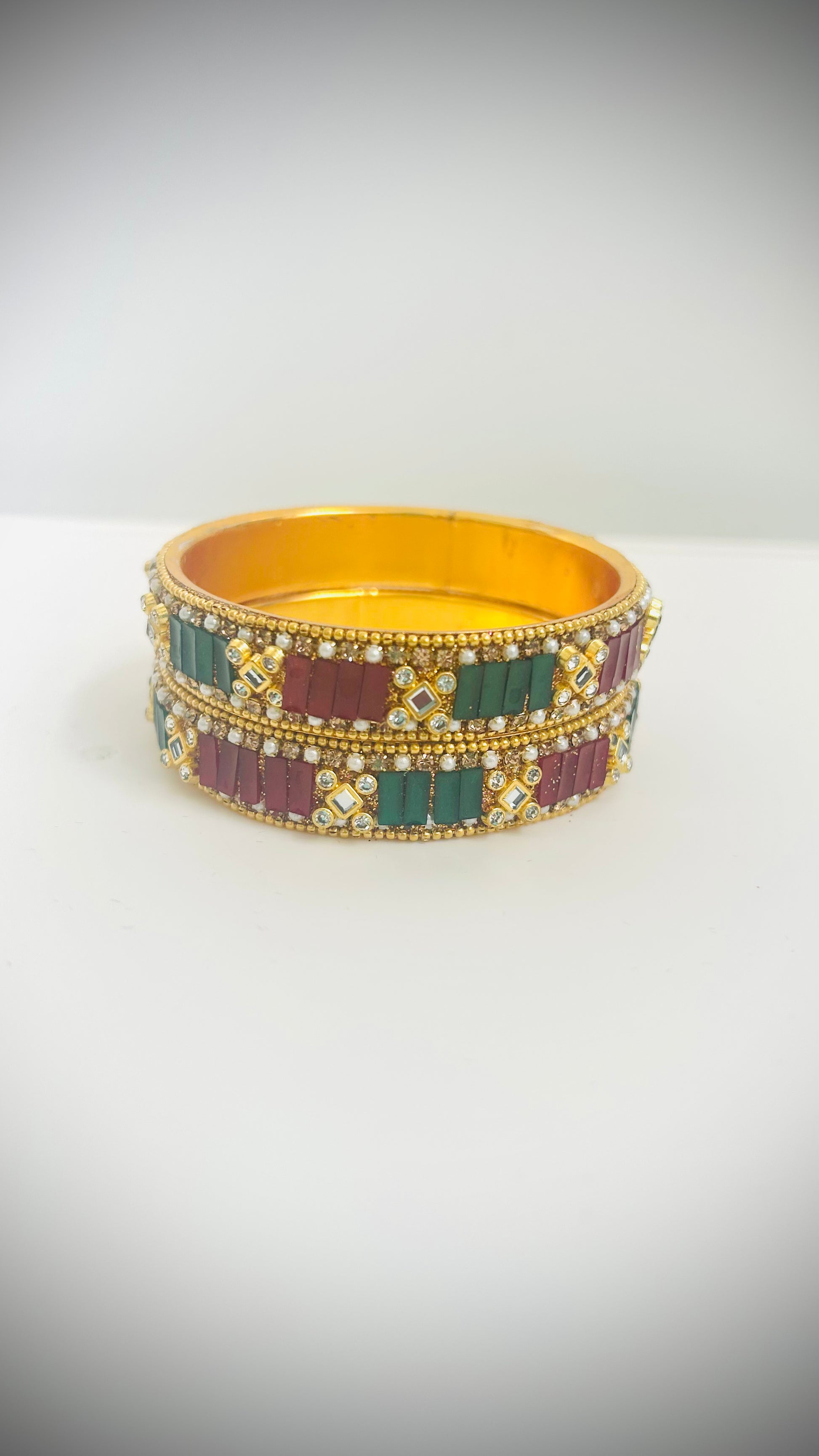 Pair of gold bangles with red and green stones