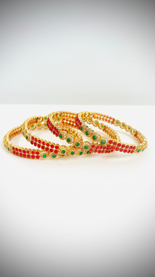 Set of gold bangles with red and green stones.