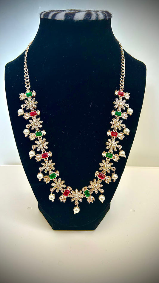 Necklace with floral designs and colored stones on a black stand.