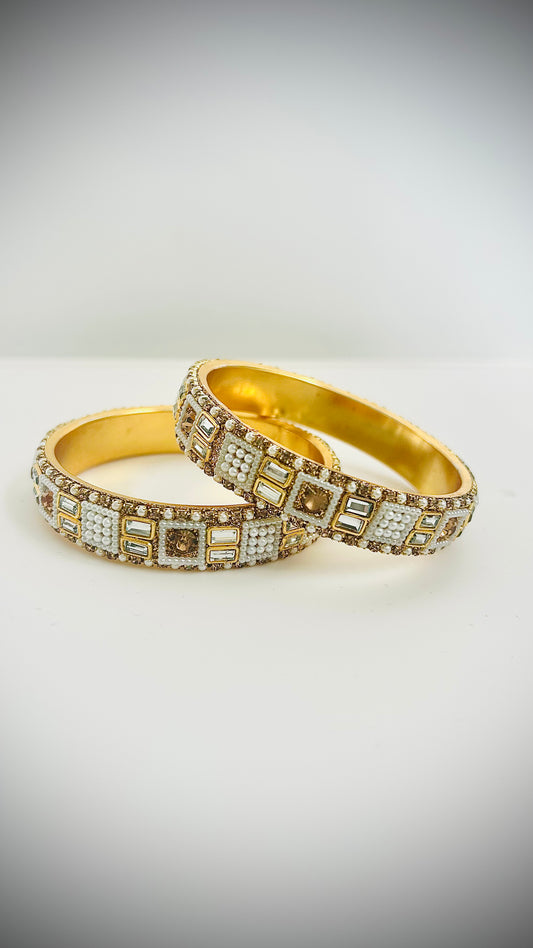 Two gold bracelets with white gemstones.