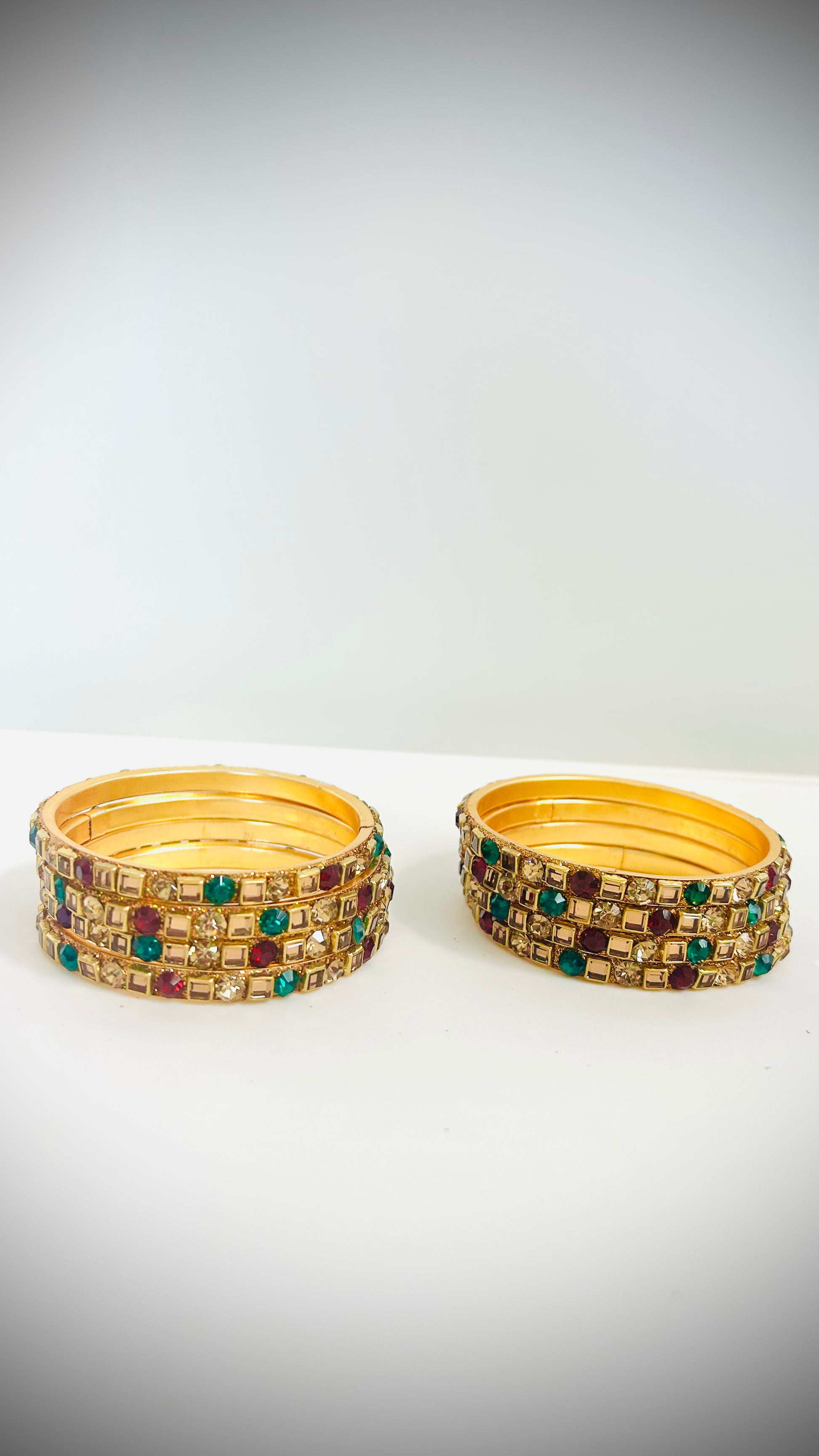 Gold bangles with green and red gemstones 