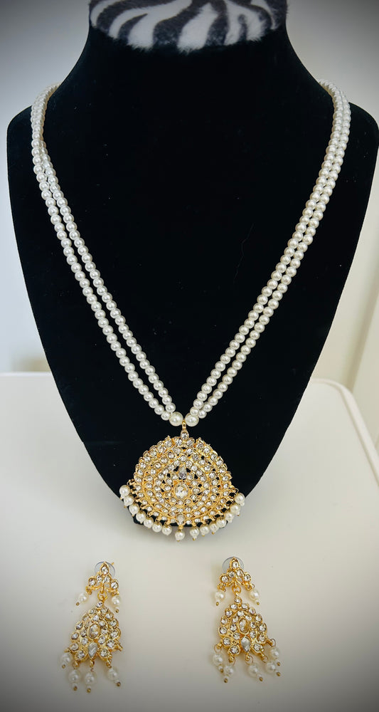 Pearl necklace with a gold pendant and matching earrings on a black mannequin bust.