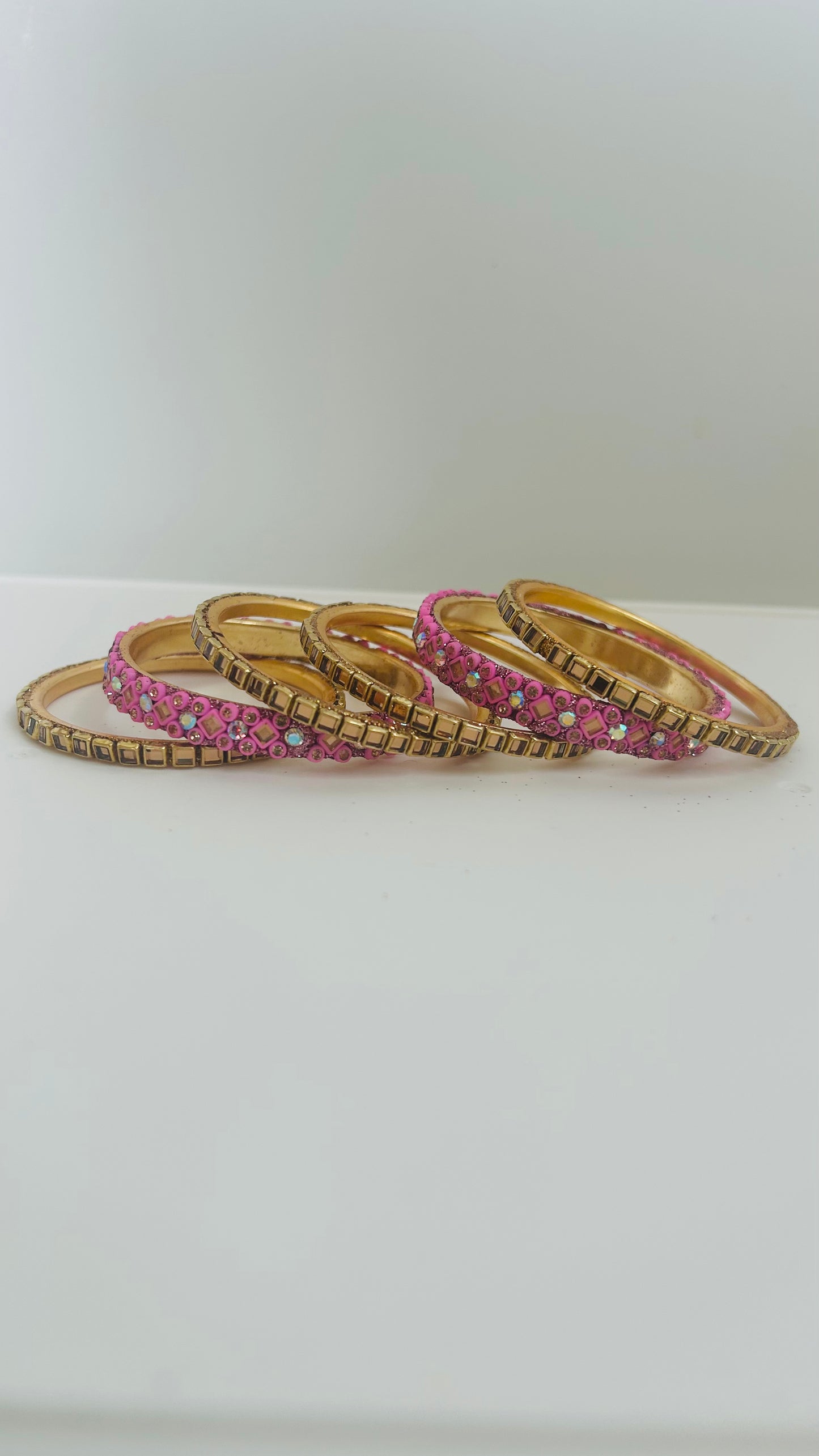 Set of gold and pink bangles on a white surface