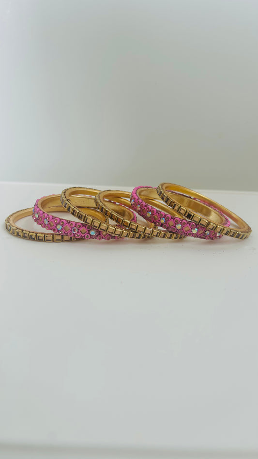 Set of gold and pink bangles on a white surface