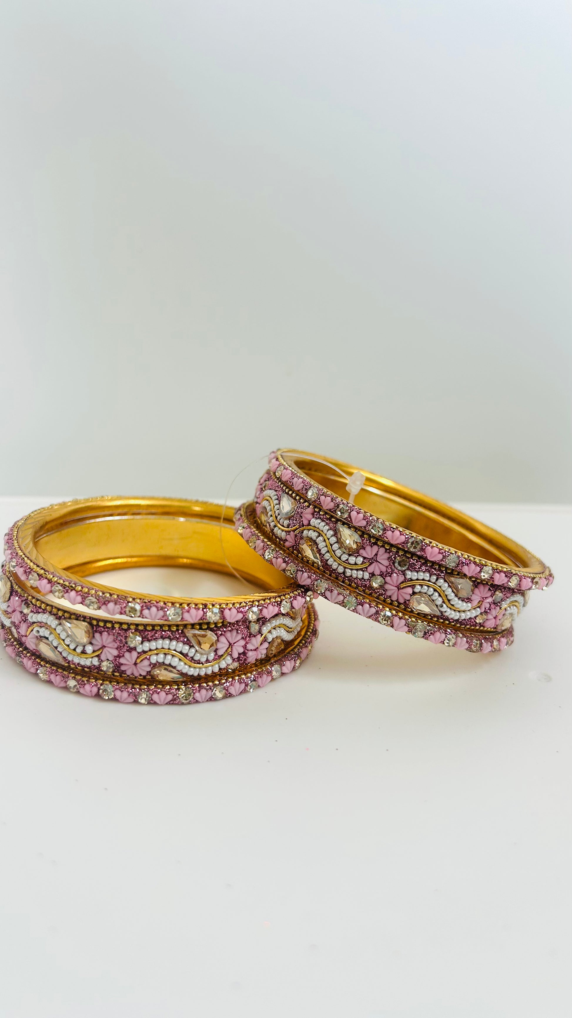 Set of gold bangles with pink and white stones 