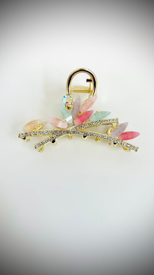 Decorative hair clip with colorful stones and gold accents on a light gray background