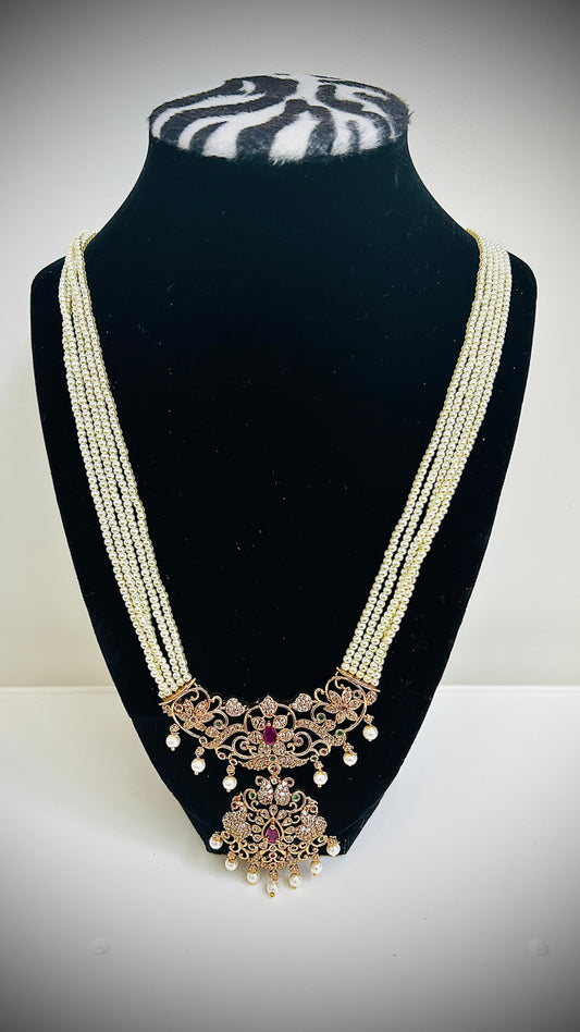 Delicate necklace with intricate design on a black stand against a white background